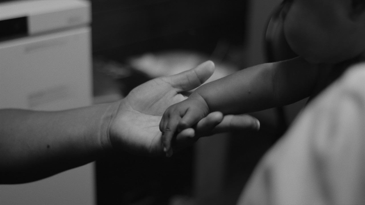 Close up of an adult holding an infants hand